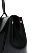 Black handbag with silver hardware on a light gray background. Bag by HBH