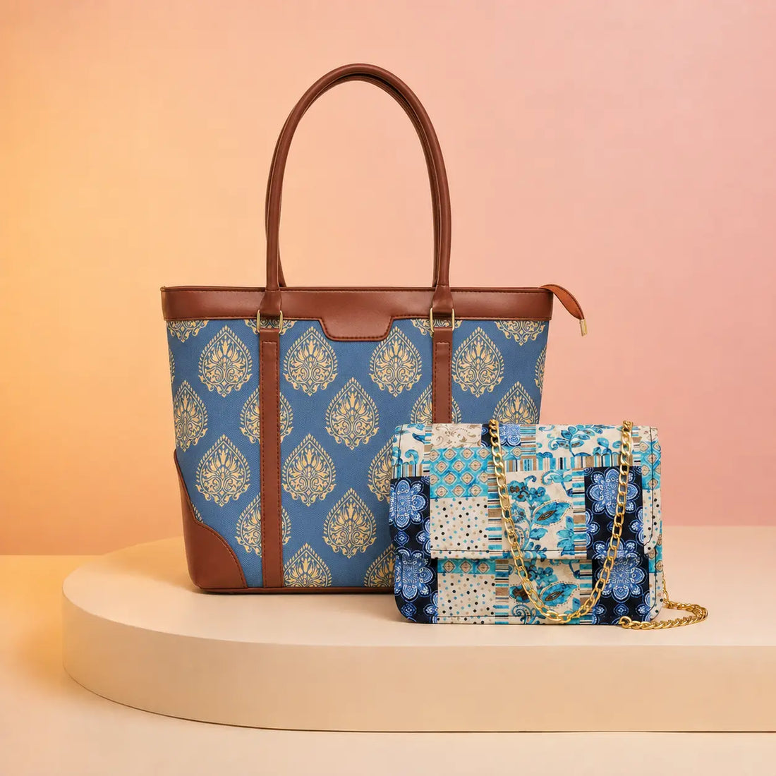 A blue and beige patterned tote bag with brown leather handles and trim, displayed next to a matching patterned flap bag with a gold chain strap on a beige platform against a soft peach background.